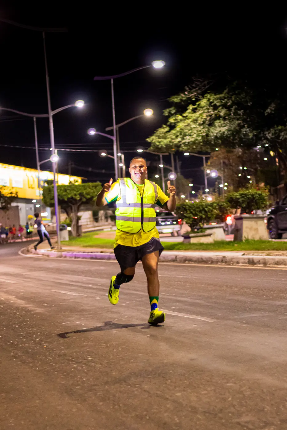 Integrante dos Miranteiros correndo à noite com colete refletivo e sinal de positivo